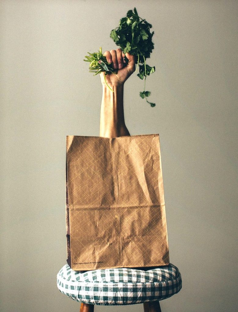 Image d'une main sortant d'un sac de courses un bouquet d'épinard pour illustrer les astuces d'une transition alimentaire