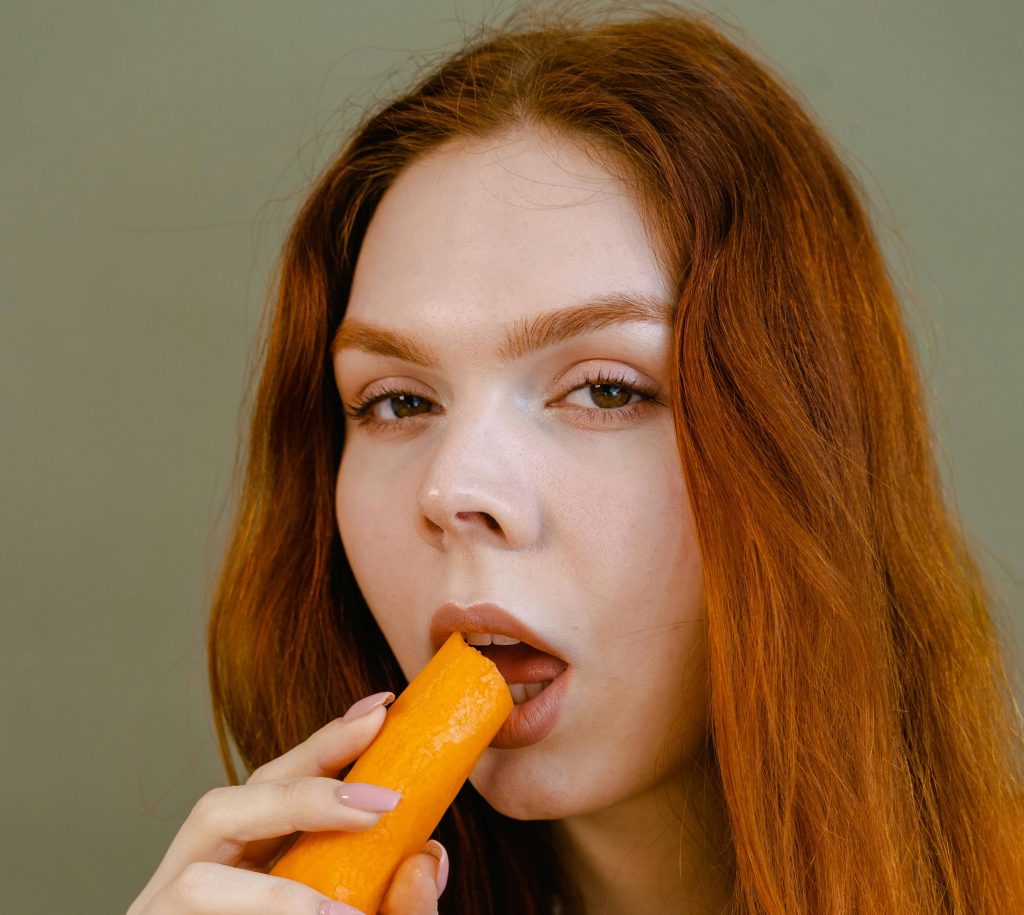 Visuel d'une femme mangeant un légume dans le cadre d'une transition alimentaire réussie